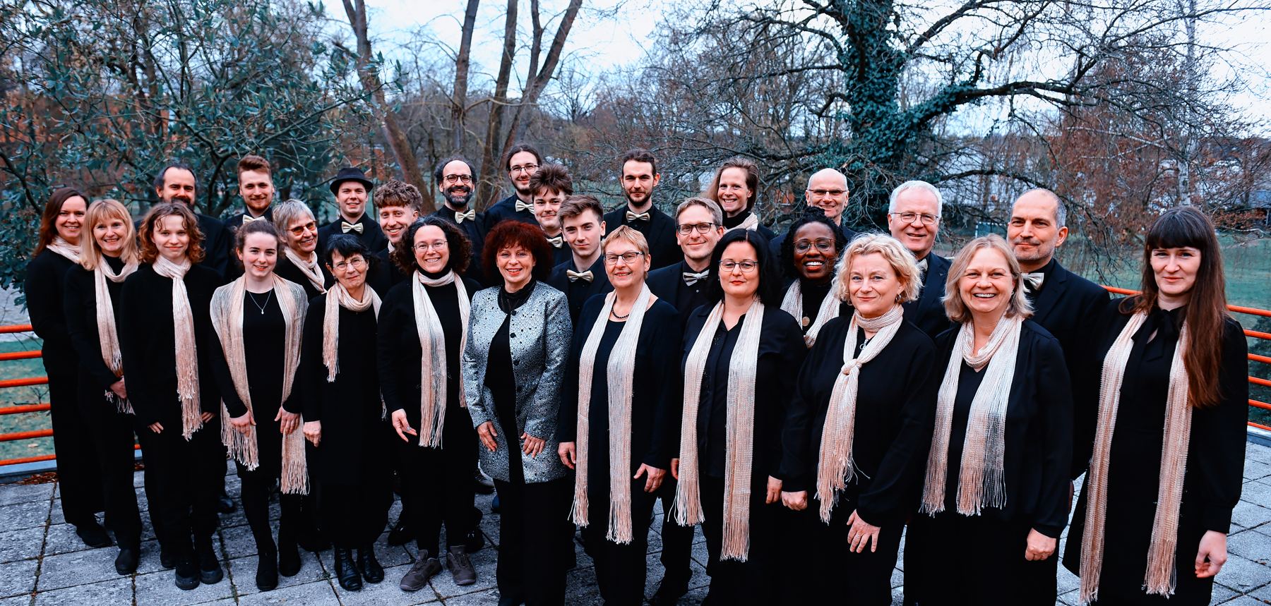 Gruppenfoto des Chores Canto Ergo Sum in schwarzer Kleidung mit hellen Schals